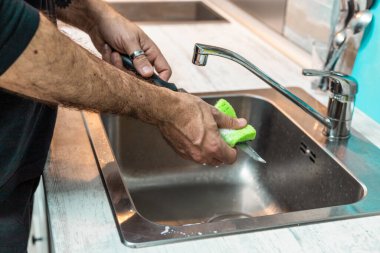 Tanınmayan kişi bulaşıkları elle yıkıyor. İnsanlar, ev işi yapan insanlar, eşitlik.