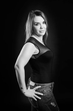 Siyah arka planda poz veren esmer genç bir kadın.