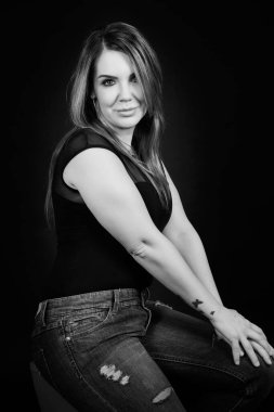 Siyah arka planda poz veren esmer genç bir kadın.