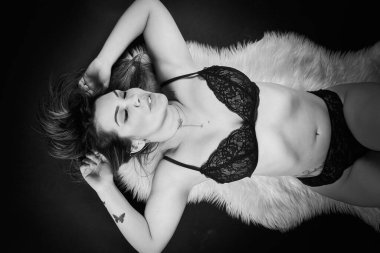 Siyah arka planda iç çamaşırlarıyla poz veren güzel esmer bir kadın.