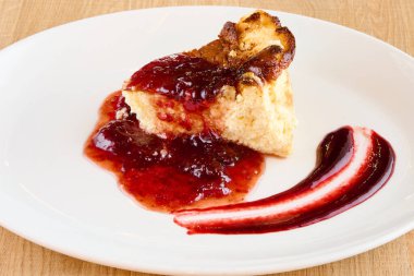 Kırmızı meyve reçelli bir tabak cheesecake.