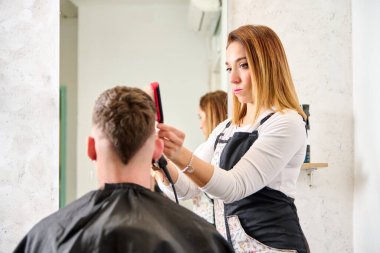 Kuaför kuaförde saç kesiyor ve berber dükkanında bir müşteriyi şekillendiriyor.