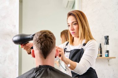 Kuaför kuaförde saç kesiyor ve berber dükkanında bir müşteriyi şekillendiriyor.