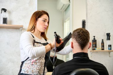 Kuaför kuaförde saç kesiyor ve berber dükkanında bir müşteriyi şekillendiriyor.