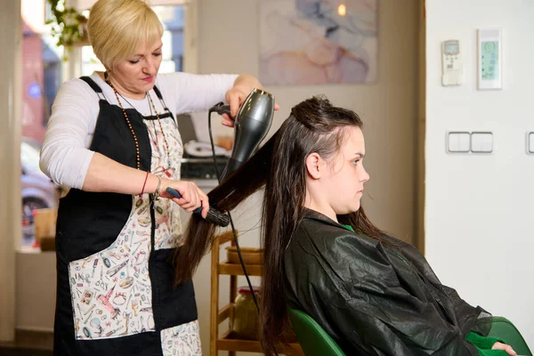 Kuaför, kuaförde saç kurutma makinesiyle kurutur ve şekillendirir.