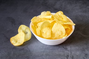 Siyah arkaplanda patates kızartması olan beyaz bir kase.