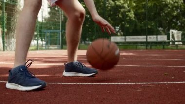 Aydınlık ve güneşli bir yaz gününde, açık havada top süren bir genç. Beyazların basketbol oynamak için beyaz beyaz bir gencin eğitim videosu. Basketbol numaraları yapan bir erkeğin videosu.. 