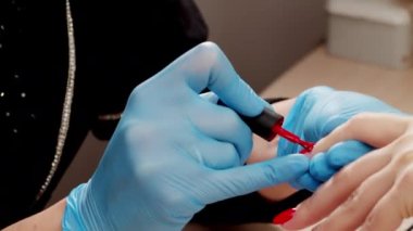 Manikürcü kırmızı jel cilasıyla oje sürüyor. Tırnak cilası başvurusu. Manikürlü kırmızı tırnaklar. Manikür servisinin 4k yavaş çekim görüntüsü.