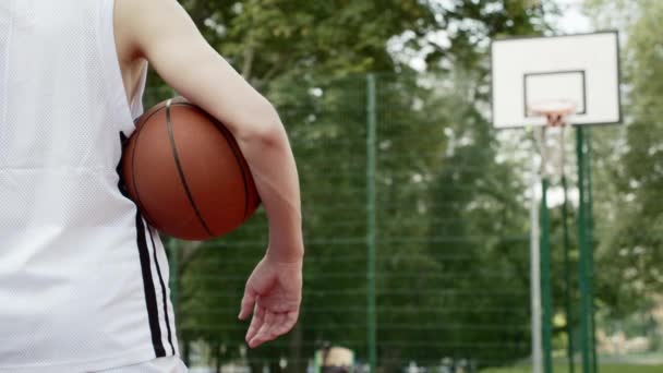 Een Jongen Die Een Basketbalveld Staat Een Basketbal Onder Zijn — Stockvideo