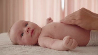 Masöz, sağlıklı bir bebeğe masaj yapıyor. Bir masöz karnına ve karnına masaj yaparken küçük beyaz bir bebek dinleniyor.. 