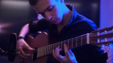 Genç adam odasında gitar çalar. Genç çocuk bir müzik aleti çalıyor. Müzisyen bestesini profesyonel mikrofon kullanarak bir müzik stüdyosunda kaydeder. Profesyonel ışıklandırma 