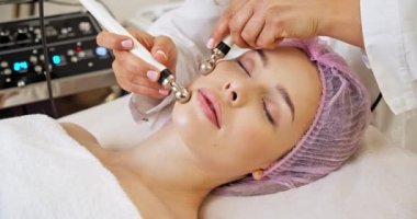 Güzeller güzeli kadın spa salonunda mikroakım tedavisi görüyor. Güzellik uzmanı yüz işlemleri için elektriksel impulslar kullanıyor. Kaplıca salonundaki kadın. Kozmetik işlemleri üzerine spa salonundaki kadın..