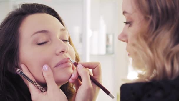 在化妆室化妆的年轻女人 嘴唇的构成过程 美容院的化妆师在为美女化妆 女性形象 用铅笔做嘴唇 做面食 — 图库视频影像