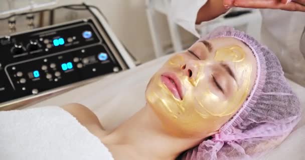 Cosmetologist Aplica Uma Mulher Uma Máscara Terapêutica Seu Rosto Mulher — Vídeo de Stock