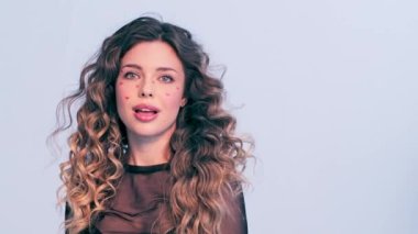 Moda modeli bir fotoğraf stüdyosunda çekilir. Stüdyoda poz veren güzel bir model, parlak ışıklar. Rüzgarda savrulan uzun saçlı güzel bir genç kadın. Saç üfleyen kız. Yavaşlama Hareketi . 