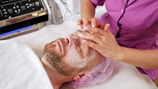 Esteticista Faz Uma Massagem Aplicando Creme Hidratante Rosto Masculino Cosmetologist — Vídeo de Stock