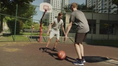 Sıcak bir yaz gününde sokak basketbolu oynayan insanlar. Güneşli bir yaz gününde açık hava sahasında basketbol oynayan iki genç. Atış yok..
