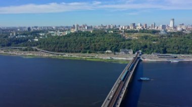 Pecherskaya Lavra manzaralı Dnepr nehrinin üzerinde bir dron uçurmak. Köprü metrosunun üst manzarası ve sürüş arabalı bir otoyol. Ukrayna 2020 yazında Kiev kentine sinematik hava manzarası