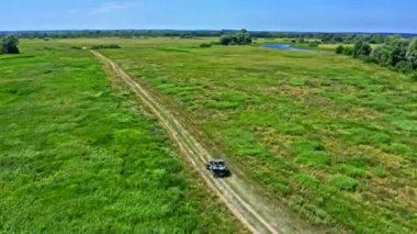 İHA 'dan hava görüntüsü, bir ralli aracını takip ediyor. Fast Buggy büyük toz bulutlarıyla gidiyor. İHA 'dan yarışa arabalarla üstten görünüm.  