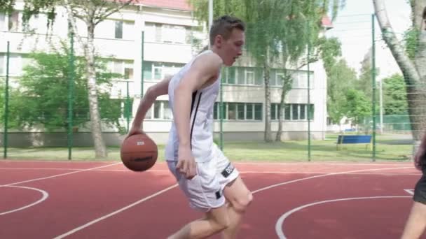 人们在一个温暖的夏日里打篮球 在阳光明媚的夏日 两名青少年在室外场地打一场篮球赛 攻击和防御 未射中 — 图库视频影像