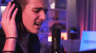 Şarkıcı bestesini odasında kaydediyor. Genç Çocuk mikrofona bir şarkı söylüyor. Profesyonel müzisyenlerin kulaklıkla evde şarkı söylemelerinin sinematik görüntüleri..