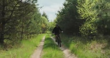Orman yolunda bisiklet sürerler. Ormanda bisiklete binen bir adam. Bisiklet kasklı yetişkin bir adam yazın MTB bisikletine biner..