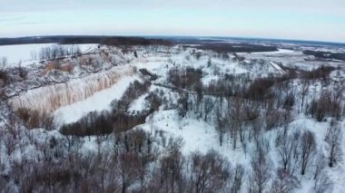 Drone kışın karlı tebeşir ocağının üzerinden uçar. Tepelik arazisi olan karla kaplı güzel bir kış manzarası. Kışın karlı vadinin havadan görünüşü. Güzel karlı manzara.