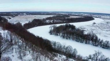 Drone donmuş bir nehirle karlı kış manzarasının üzerinde uçuyor. Kışın güzel doğa. Kışın karlı vadinin havadan görünüşü. Güzel karlı manzara.