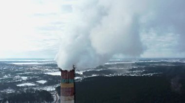 Kışın şehrin arka planında baca tüttürmek. Atmosfere yayılan çevresel kirlilik. Atmosferik emisyonların hava görüntüsü. Ukrayna 2022, Shostka şehri..