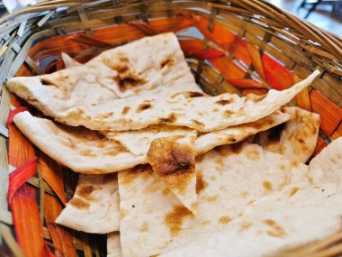 Tahta bir sepetin içinde geleneksel köri ile birlikte yenmek üzere servis edilen İran usulü ızgara ekmeği.