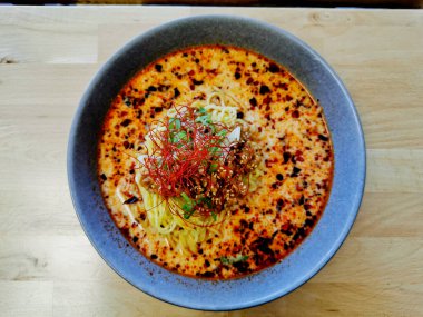 Baharatlı, kırmızı kıymalı, bronzlaşmış, Japon erişteli erişte çorbası sıcak servis edilir.