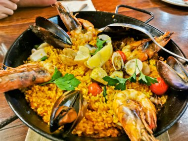 Seafood Spanish Paella with black lips mussels and tiger prawns served in black pan