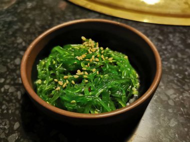 Green wakame Japanese seaweed sour salad topping with sesame seeds