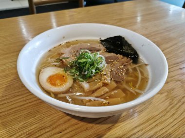 Japon usulü şehriyeli tuzlu et suyu çorbası domuz yumurtası, fasulye filizi ve ahşap masada taze soğan.