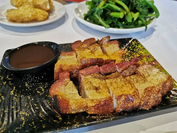 Crispy hot roast pork belly with plum sweet sauce in Yum Cha Chinese restaruant on black dish