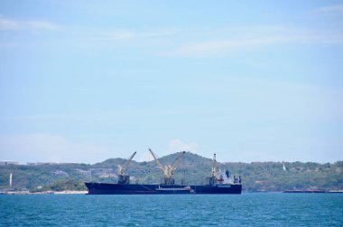 One huge logistic transportation ship with cranes to move cargos around floating in the ocean on sunny day