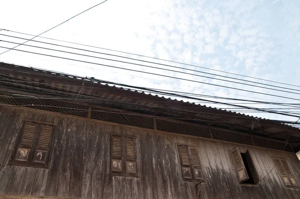 Thai style old traditional house with electrical wires on the top in cloudy day