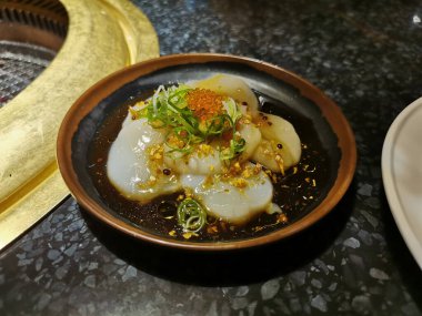 Japon taze Hokkaido deniz tarağı salatası susamlı ve sarımsaklı siyah sos.