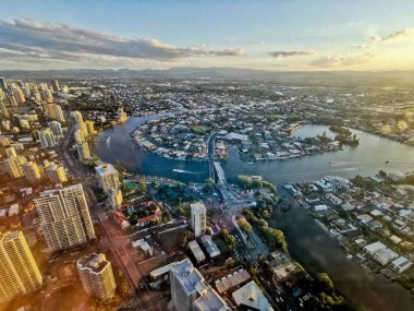 GOLD COAST, AUSTRALIA - APRIL 25, 2021: Aerial panorama view of High-rise building sky scrapers with inland island and Surfer Paradise city skyline landscape with Sunset light in the evening.