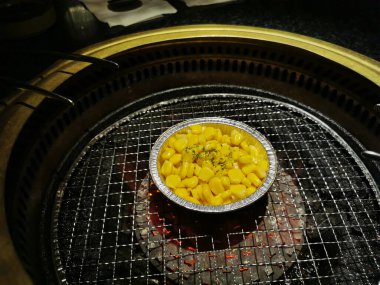 Sweet corn with butter in foil bowl ready to be grilled in BBQ Japanese Yakiniku stove