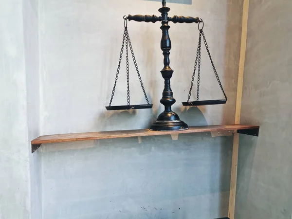 Black balance traditional weighing scale placed on the wooden shelf with white granite wall