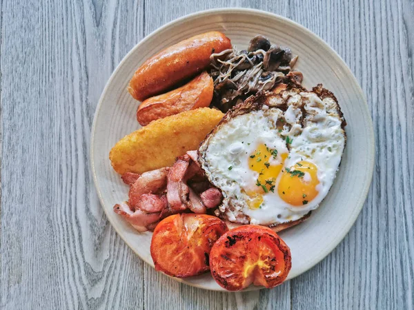 English Big Breakfast with sunny fried eggs, sausage, bacon, tomatos, hash brown, mushroom