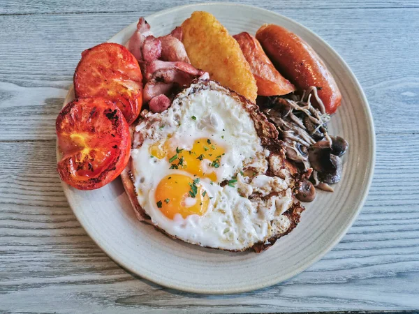 English Big Breakfast with sunny fried eggs, sausage, bacon, tomatos, hash brown, mushroom