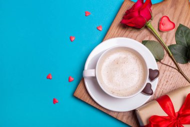 Sevgililer Günü kahvaltısı yatakta. Hediye, kahve gülü, mumlar, mavi arka planda kalpler. Sevgililer Günü konsepti.