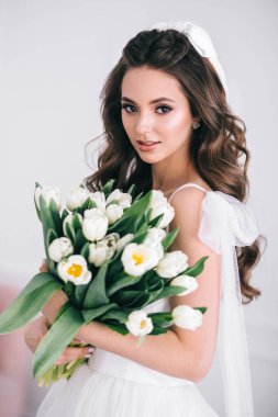 Stüdyoda elinde bir buket beyaz lale tutan güzel gelin. Doğurma günü. Gelin stili