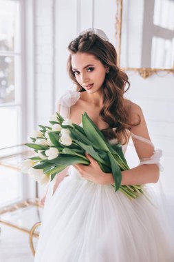 Stüdyoda elinde bir buket beyaz lale tutan güzel gelin..