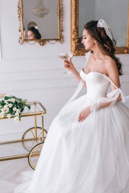 Gelinlikli güzel gelin yatak odasında şampanya içiyor.