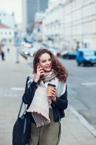 Νεαρή γυναίκα με καφέ μιλάει στο κινητό τηλέφωνο σε εξωτερικούς χώρους στην πόλη — Φωτογραφία Αρχείου