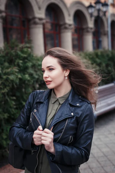 Mujer joven en chaqueta de cuero negro caminando por la calle — Foto de Stock