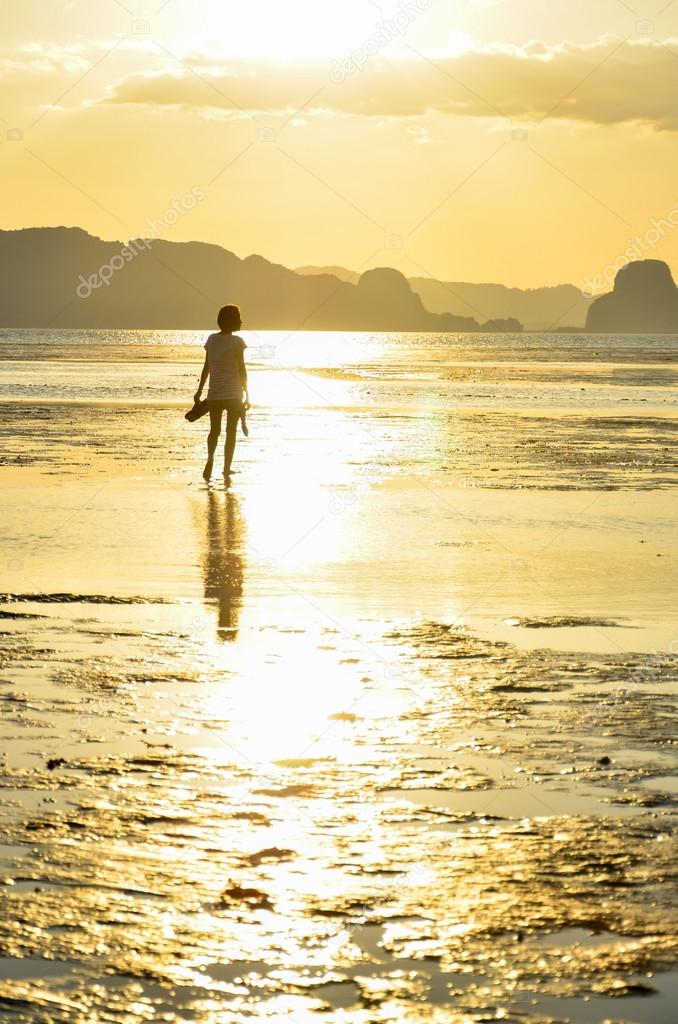 Girl walking on the beach on sunset